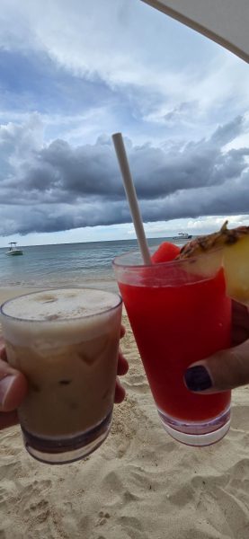 Couple enjoying tropical drinks on the beach at Sandals Dunn's River in Ocho Rios, Jamaica.